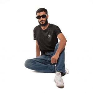 Tienda A stylish young man in a black shirt and jeans, seated against a white background.