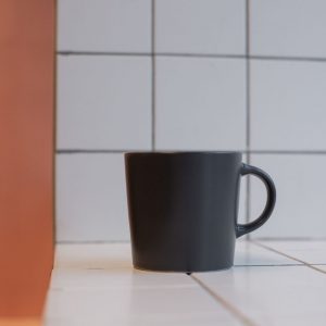 Tienda A simple black cup sits on a white tiled surface in a kitchen setting, emphasizing minimalist design.